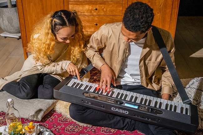 Two people playing keyboard together