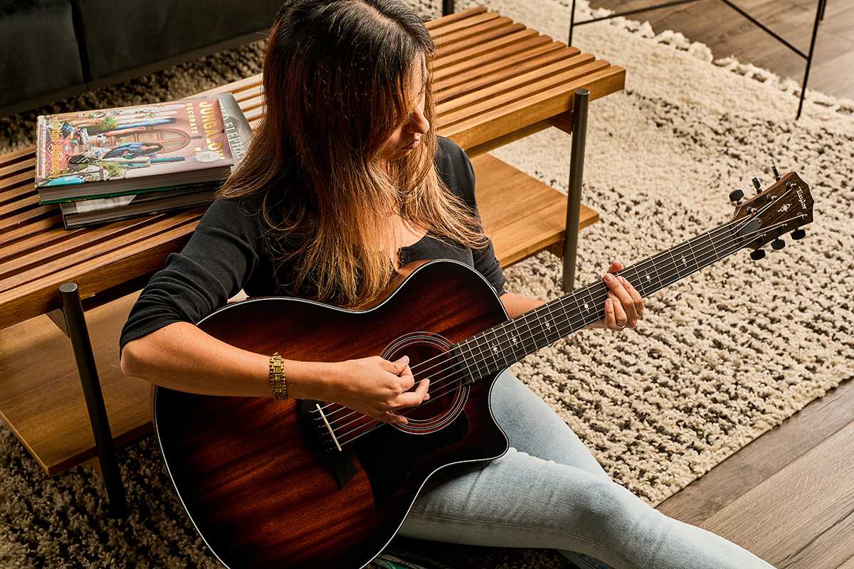 person playing a Taylor 324ce in home environment