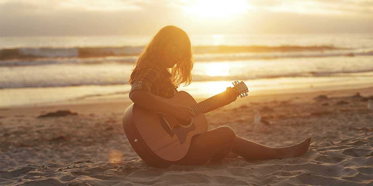 Girl playing GS Mini on the beach at sunset