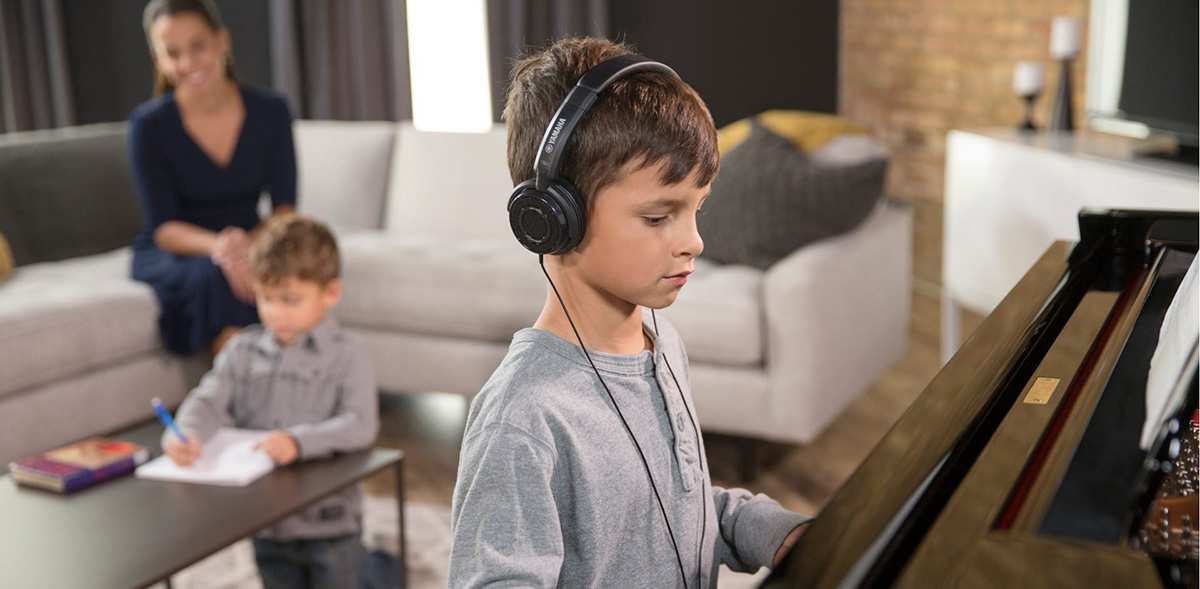 child with family playing acoustic piano silently with headphones